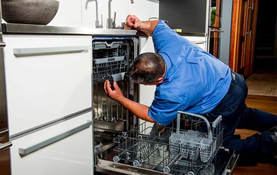 Appliance technician removing the lower rack to inspect a built-in dishwasher